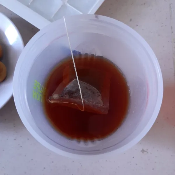 Celup teh di air hangat. Tambahkan gula lalu aduk rata hingga gula larut.