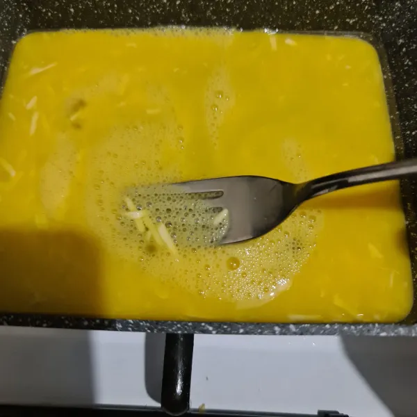 Beri butter dan panaskan wajan, masukkan telur dan kocok perlahan menggunakan garpu.