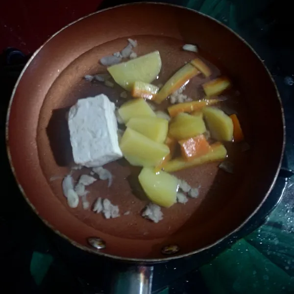 Masukkan wortel, kentang, tahu dan air. Masak hingga air sedikit menyusut.
