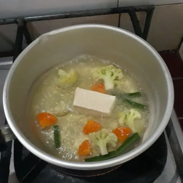 Rebus tahu, wortel, kembang kol dan kacang panjang yang telah dipotong-potong, lalu tambahkan garam dan gula pasir.