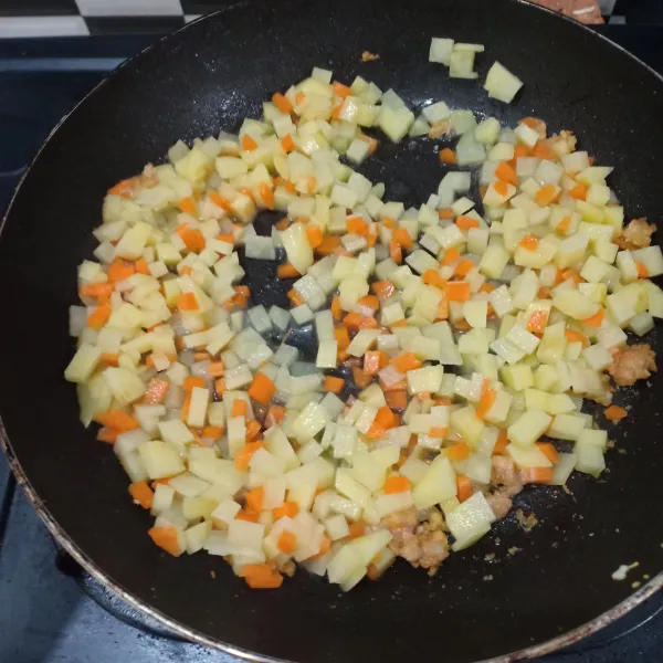 Masukkan potongan kentang dan wortel, aduk rata dan beri air agar empuk.