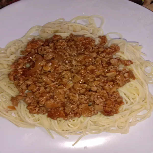 Rebus spaghetti sampai matang, tiriskan. Tata di atas piring, beri saus bolognese. Taburi dengan keju parut. Sajikan.