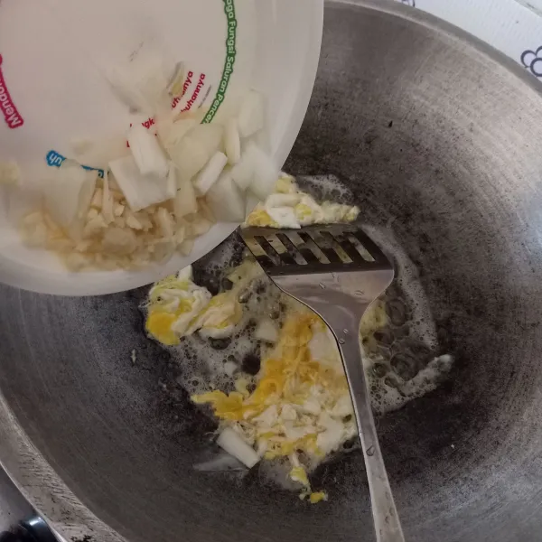 Goreng telur orak-arik, lalu masukkan bawang putih dan bawang bombay, tumis sampai harum.