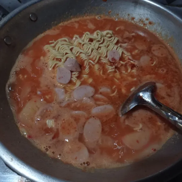 Masukan kerupuk yang sudah direndam air hangat, mie instan, dan sosis ayam. Aduk rata dan masak sampai matang.