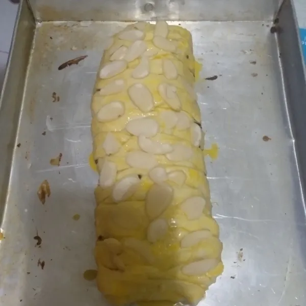 Pintal dari kiri ke kanan dengan menarik sisi kanan Kiri pastry sampai semua menutupi isian. Kemudian olesi dengan kuning telur, taburi gula pasir dan almond.