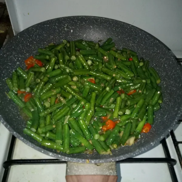 Masukkan kacang panjang, aduk rata, masak hingga setengah matang.