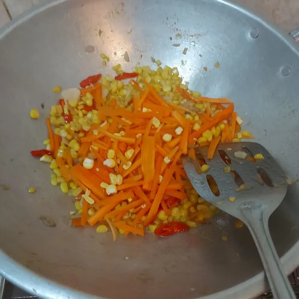 Setelah jagung mengeluarkan air, tambahkan irisan wortel.