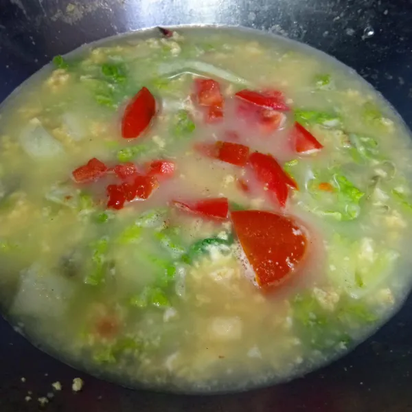 Tambahkan sawi putih, daun bawang dan irisan tomat, masak hingga mendidih.