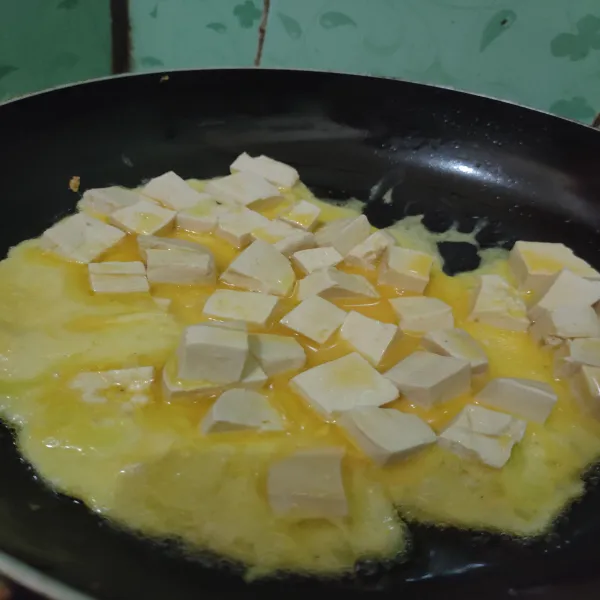 Goreng tahu dan telur dengan minyak, lalu tunggu hingga lapisan telur bawah sedikit matang. Aduk perlahan dan tiriskan.