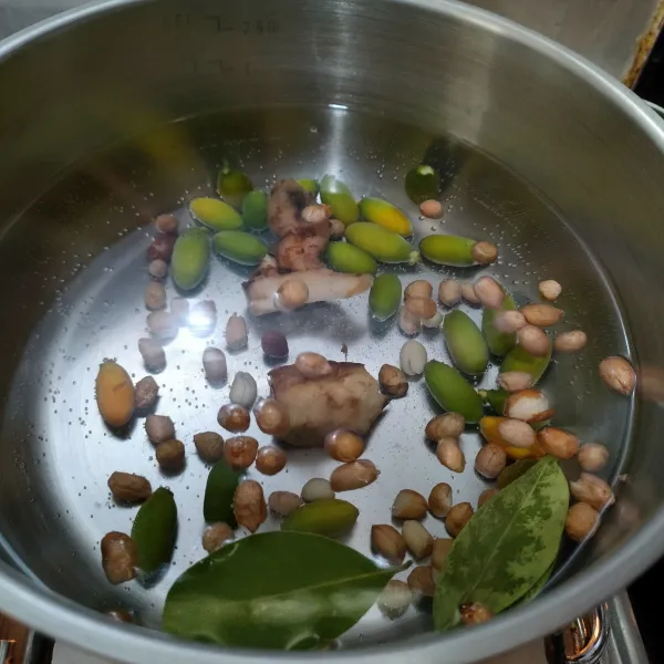 Didihkan air, masukkan buah melinjo, kacang tanah, daun salam dan lengkuas.