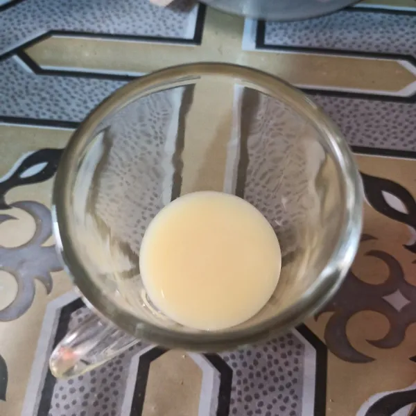 Tuang susu kental manis di gelas.