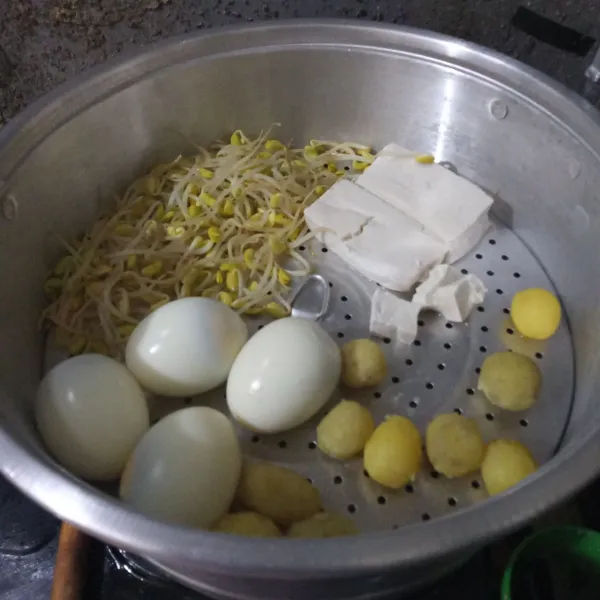 Tata tauge, tahu, telur rebus, dan kentang rebus. Kemudian kukus selama 7 menit.