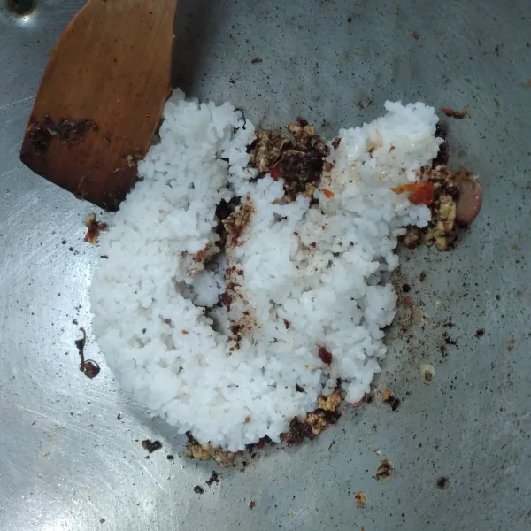 Masukkan nasi aduk hingga tercampur rata dengan bumbu, koreksi rasanya, aduk sebentar biar tanak. Nasi goreng siap disajikan.