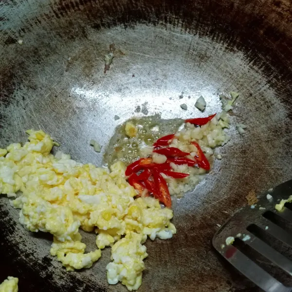 Pinggirkan telur, masukkan lagi 2 sdm minyak. Tumis bawang putih dan cabe merah keriting sampai harum dan matang.