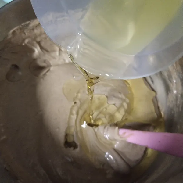 Setelah putih dan berjejak masukkan tepung terigu dan coklat bubuk beserta minyak goreng, aduk sampai rata.