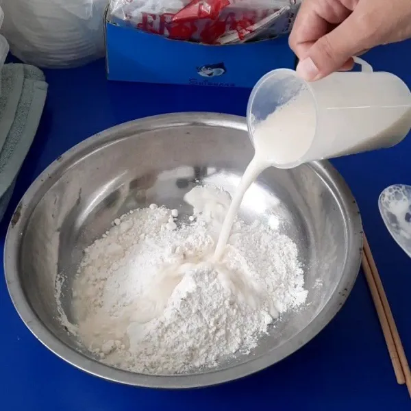 Tuang larutan ke dalam tepung secara bertahap sambil aduk dengan sumpit