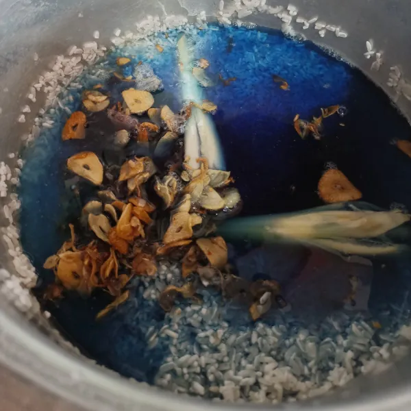 Masukkan juga air sari bunga telang, kemudian masak menggunakan magicom sampai matang.