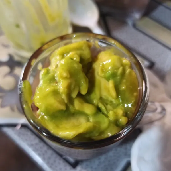 Masukkan alpukat yang sudah di kocok ke dalam gelas yang berisi susu kental manis cokelat.