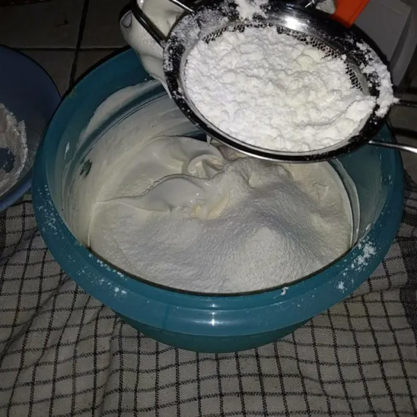 Sambil diayak, masukkan tepung terigu, susu bubuk dan tepung maizena. Mixer kembali dengan kecepatan rendah hingga tercampur rata.