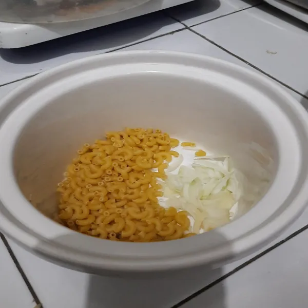 Dalam pot slow cooker masukkan macaroni dan irisan bawang bombay.