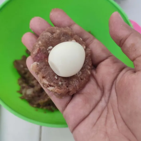 Ambil sedikit adonan daging, pipihkan. Letakkan telur puyuh diatasnya, kemudian bungkus dan bentuk bulat. Lakukan hingga adonan daging habis.
