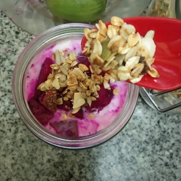 Tuang irisan buah naga ke dalam jar, tambahkan granola.