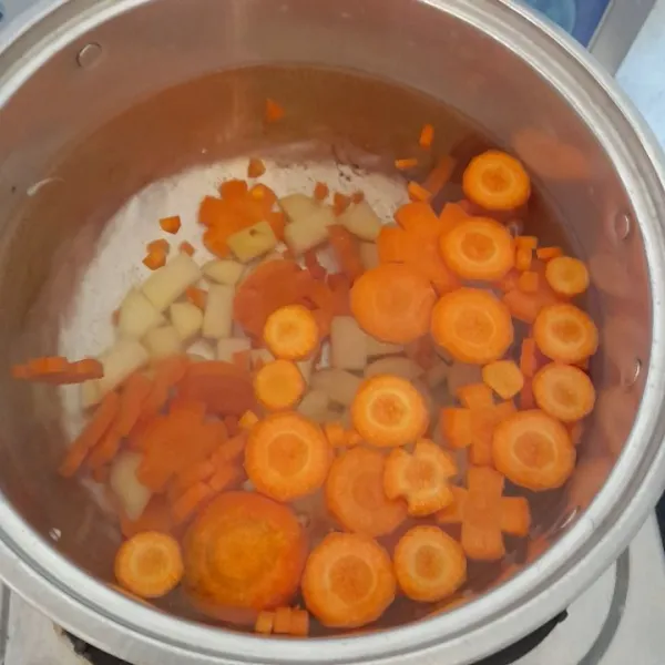 Rebus air hingga mendidih, masukkan kentang dan wortel, masak hingga setengah matang.