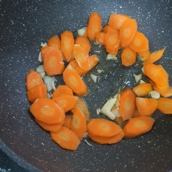 Tumis bawang putih yang sudah dicincang dan masukkan wortel yang sudah diiris.