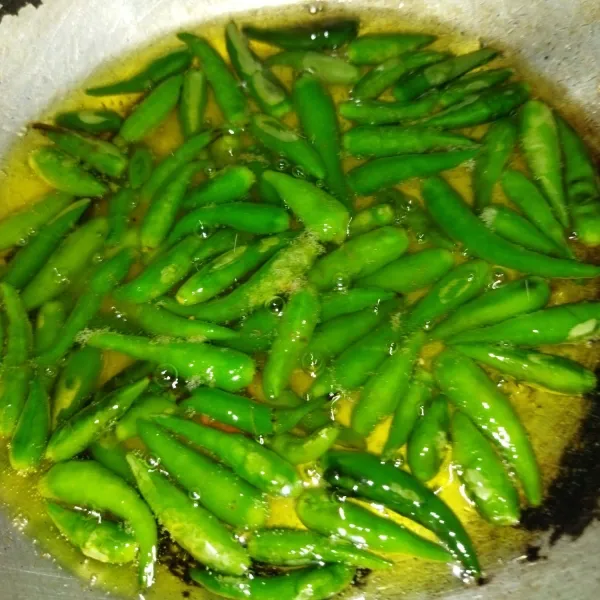 Siapkan sambal hijau, tusuk-tusuk cabai ijo agar cabai tidak meletus saat di goreng, lalu goreng cabai rawit hingga layu, lalu angkat.