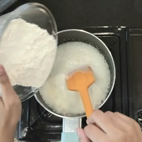 Masukkan tepung terigu sedikit demi sedikit sambil diaduk agar tidak menggumpal. Lalu, masak hingga matang atau hingga ada sedikit yang menempel dipanci.