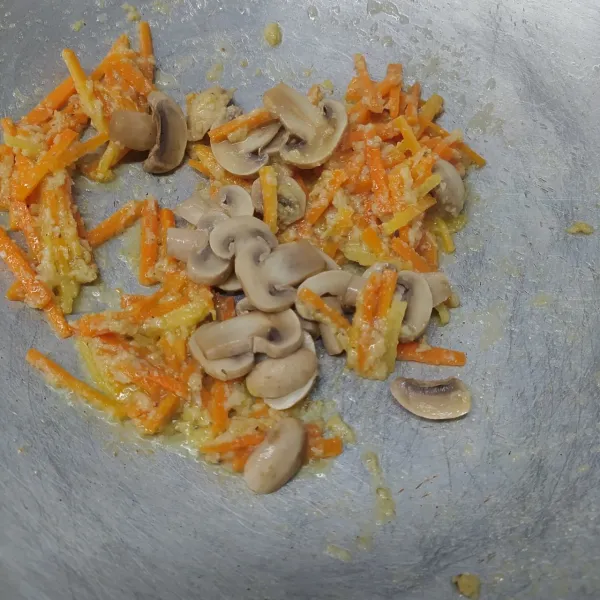 Masukkan wortel, tumis sampai layu (tambahkan sedikit air biar tidak gosong). kemudian masukkan jamur kancing. Aduk rata dan sisihkan di tepi wajan.