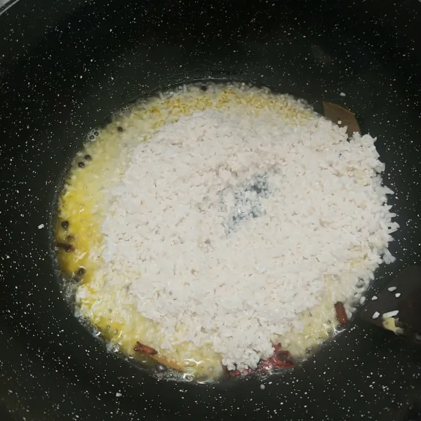 Lelehkan butter masukan bay leaf, lada utuh, cengkeh dan kayu manis masak sampai harum lalu masukan beras dan tambahkan air
