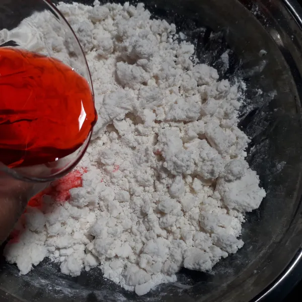 Campurkan air dengan beberapa tetes pewarna merah, masukkan ke dalam campuran tepung dan singkong sedikit demi sedikit.