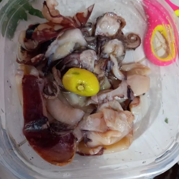 Potong-potong cumi, lalu beri perasan jeruk nipis.