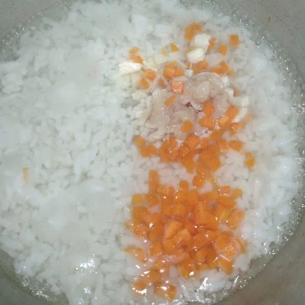 Masukkan ayam, wortel dan bawang putih ke dalam adonan bubur, lalu tambahkan air santan dan sejumput garam.