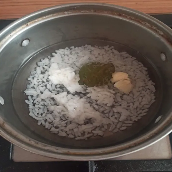 Tuang nasi dalam panci, tambahkan air sekitar 100 ml tambahkan 1/2 siung bawang putih geprek dan daun salam. Masak hingga teksturnya lembek sambil sesekali diaduk.