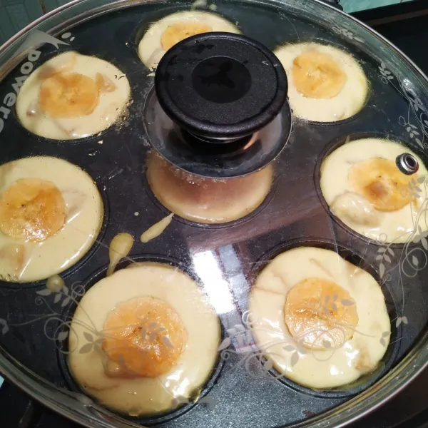 Beri topping irisan pisang, kemudian tutup loyang. Biarkan kuning bagian bawah.