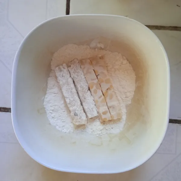 Balur tempe dalam tepung terigu, hingga menyelimuti sisinya.