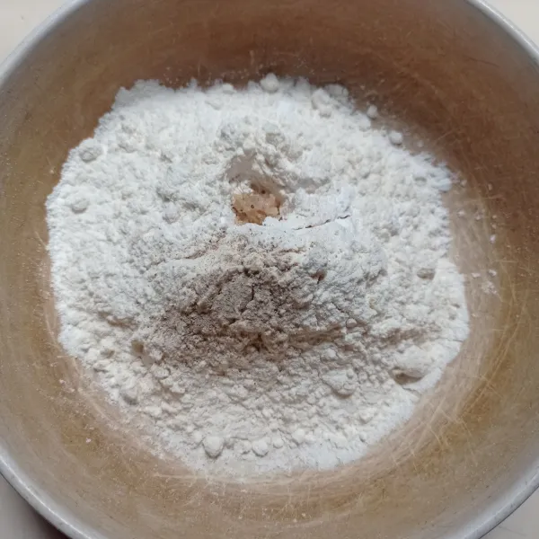 Masukan tepung terigu, tepung kanji, garam, lada, kaldu bubuk dan bawang putih yang sudah dihaluskan ke dalam wadah