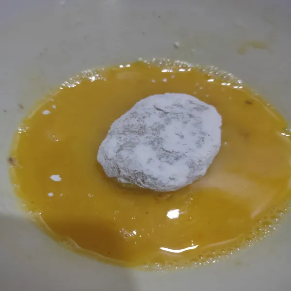 Balur perkedel ke dalam tepung terigu, lalu celupkan ke dalam kocokan telur.