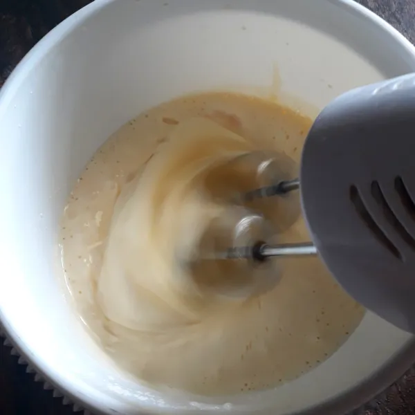 Telur ayam, gula pasir, dan emulsifier dikocok dengan mixer hingga berwarna putih dan kental berjejak.