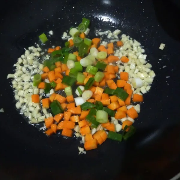Tumis bawang putih hingga harum lalu masukan wortel dan daun bawang, masak hingga layu.