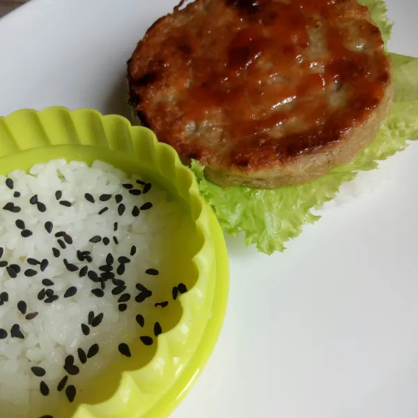 Susun nasi, sayuran, patty ayam, bisa diberi saus, lalu tutup dengan nasi.