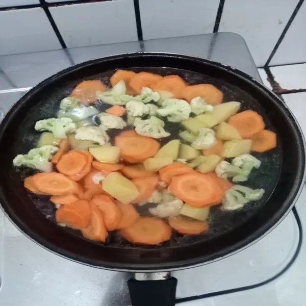 Masukkan wortel, kentang, dan kembang kol. Masak hingga mendidih dan matang.
