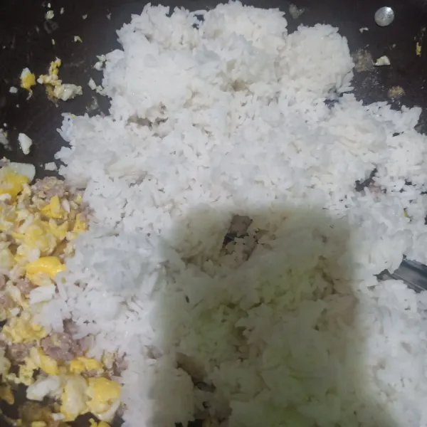 Masukkan nasi putih ke dalam wajan yang berisikan orak-arik telur daging cincang. Aduk rata.
