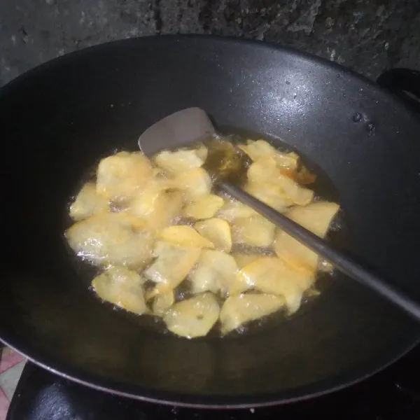 Panaskan minyak, masukkan irisan ubi ke dalam wajan. goreng hingga setengah matang.