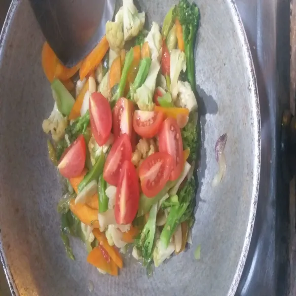 Setelah sayuran layu, masukkan bumbu pelengkap, irisan tomat, aduk rata dan koreksi rasa