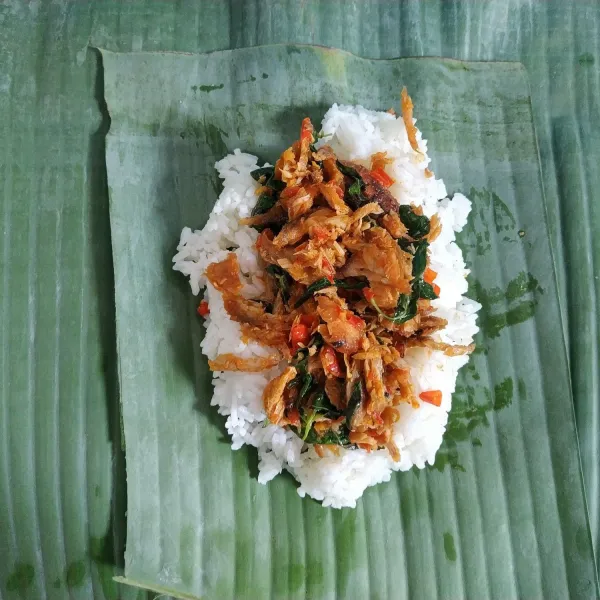 Siapkan daun pisang tuang nasi secukupnya, kemudian tambahkan tumisan ikan pindang.