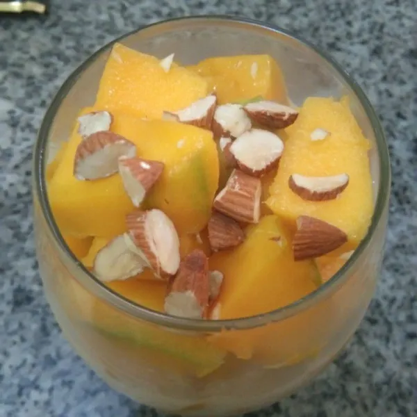 Keesokan harinya keluarkan dari kulkas, aduk rata bisa dituang pada gelas. Kemudian tambahkan potongan daging buah mangga dan irisan kacang almond.