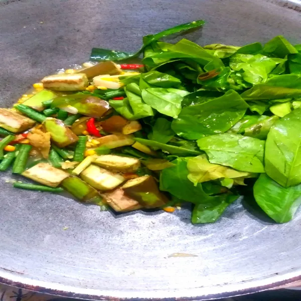 Masukkan jagung, terong, daun mlinjo, dan air, aduk rata